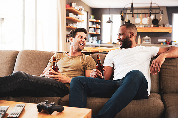 Men drinking beer, sitting on couch at home